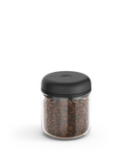 Fellow Atmos Vacuum Canister with black lid, storing coffee beans on a white background.