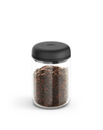 Fellow Atmos Vacuum Canister with black lid, filled with coffee beans on a white background.