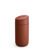 A matte rust-red Carter Slide Mug by Fellow with a rounded lid on a white background.
