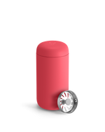 A Coral Crush Fellow Carter Move Mug with a metallic lid sits in front.