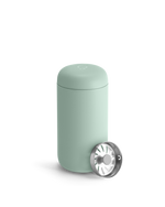 Light green Fellow Carter Move Mug with removable silver lid placed beside it.
