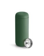 A matte green Fellow Carter Move Mug with a metal strainer leaning against it.