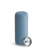 A Fellow Carter Move Mug in blue sits beside its metal strainer on a white background.