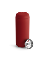 A matte red Fellow Carter Move Mug with a metal strainer on a white background.